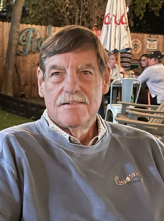 A man with a mustache and beard wearing a gray shirt.